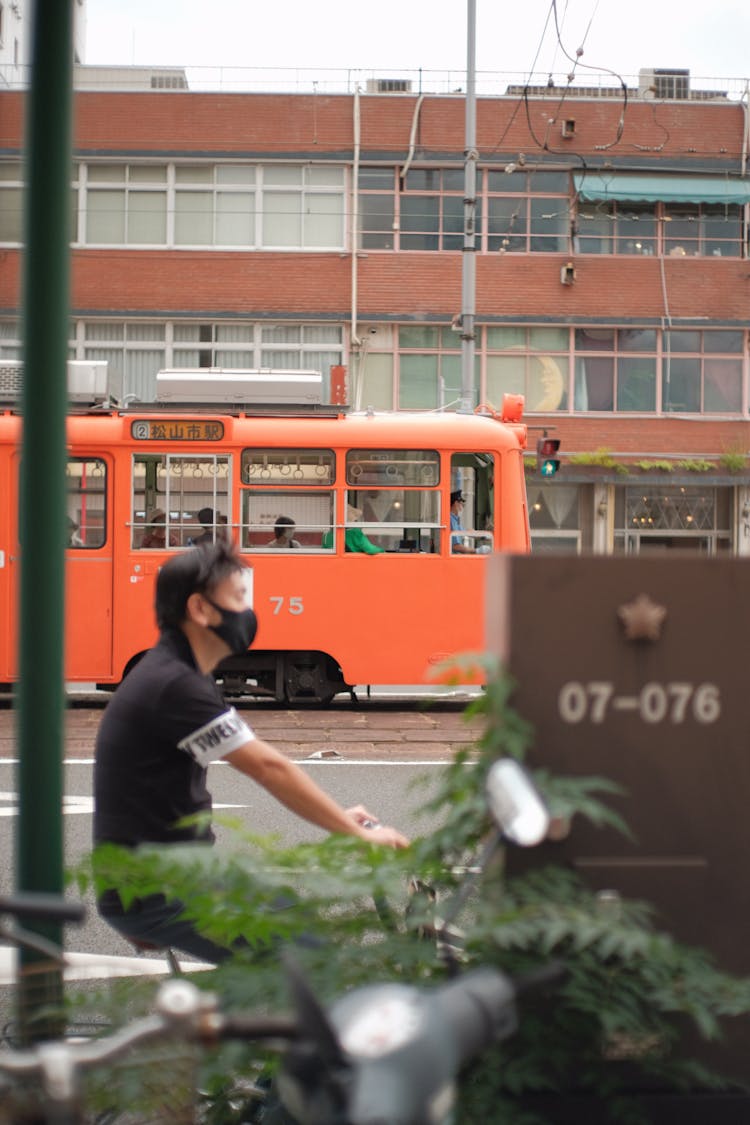 Man Cycling Near Tram