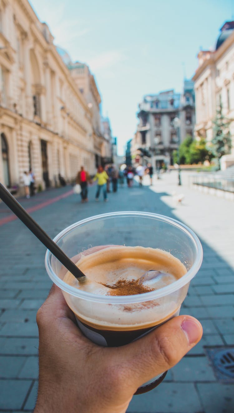 A Person Holding A Plastic Cup With Drinking Straw