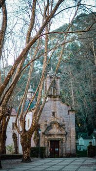 Scenic view of a historic stone church surrounded by trees in Oleiros, Galicia.