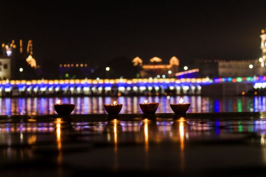 Illuminated diyas reflect in a river during Diwali night, capturing the festive ambiance and colorful lights.