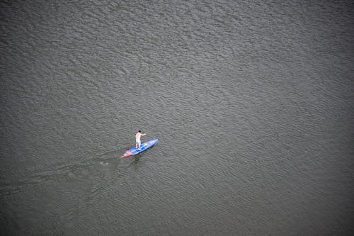 Person, Die Blaues Und Rotes Paddleboard Auf Wasser Reitet