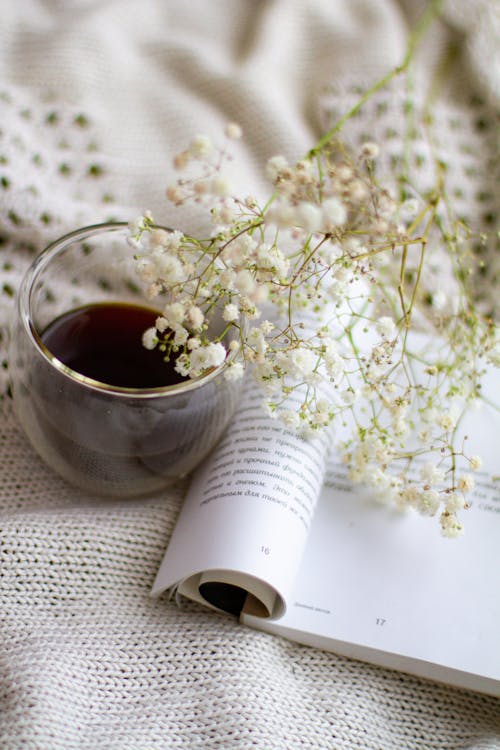 A Glass Cup, a Book and White Flowers 