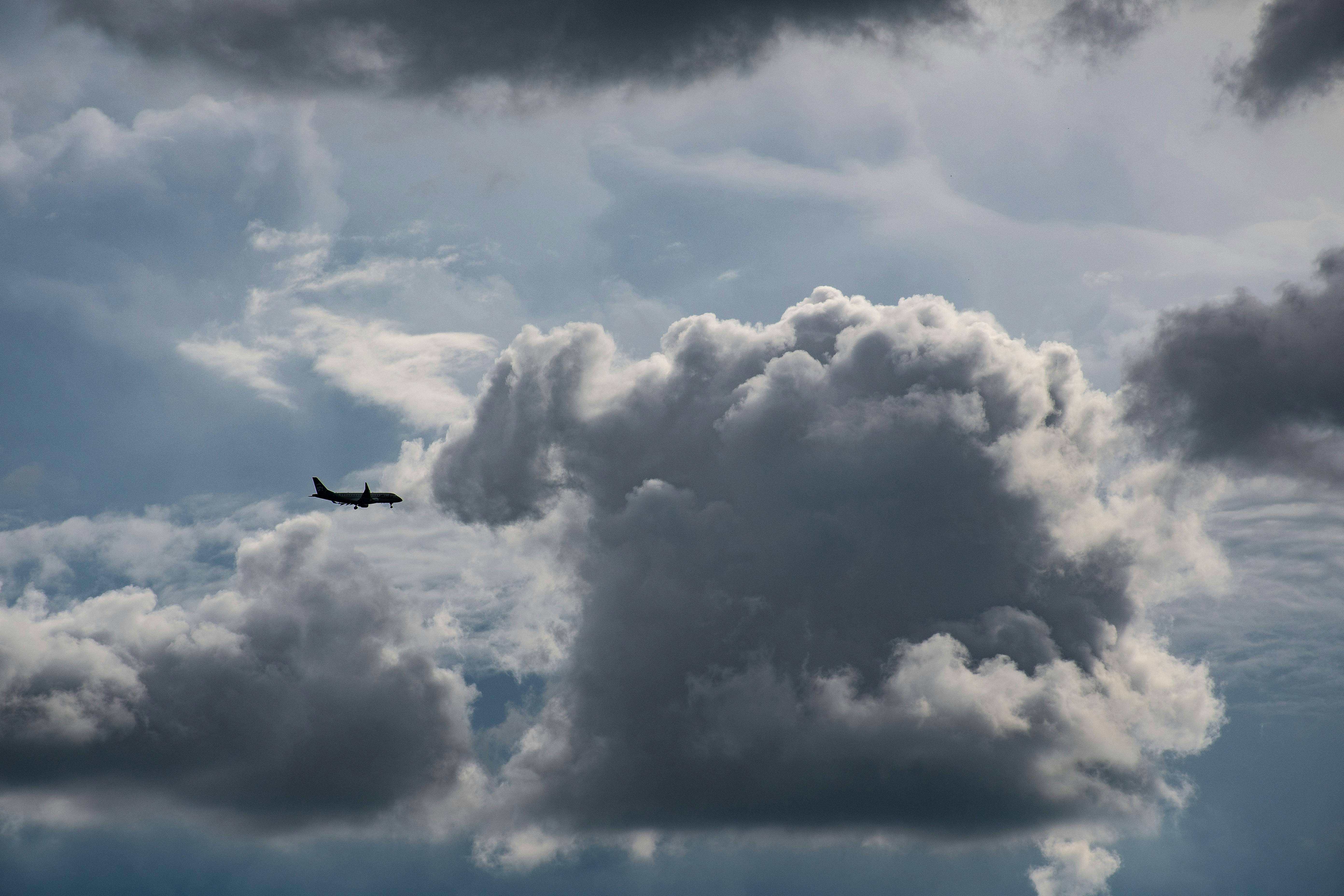 Airplane Flying Near Gray Clouds · Free Stock Photo