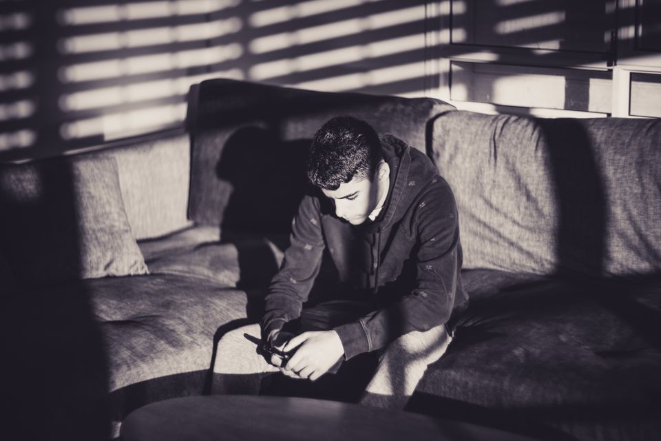 A thoughtful man looking at his phone on a sofa