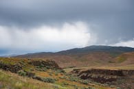 连绵起伏的山丘在戏剧性的多云天空下，捕捉了大自然的宁静之美