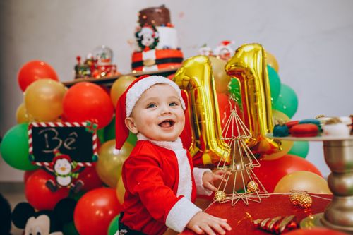 Free Adorable baby dressed as Santa with balloons enjoying a festive celebration indoors. Stock Photo