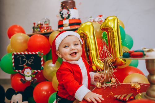 Free Adorable child in Santa outfit with balloons at a colorful birthday party. Stock Photo