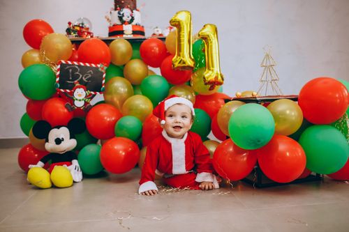 Free Adorable baby in Santa costume surrounded by colorful balloons at a festive birthday celebration. Stock Photo