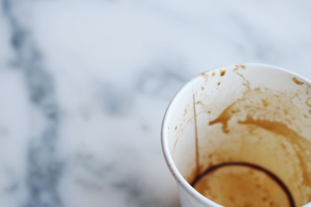 an artistic close up of an empty coffee cup on a marble surface captur