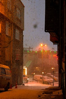 A magical snowy night scene in Istanbul's street, warmly lit by street lamps.