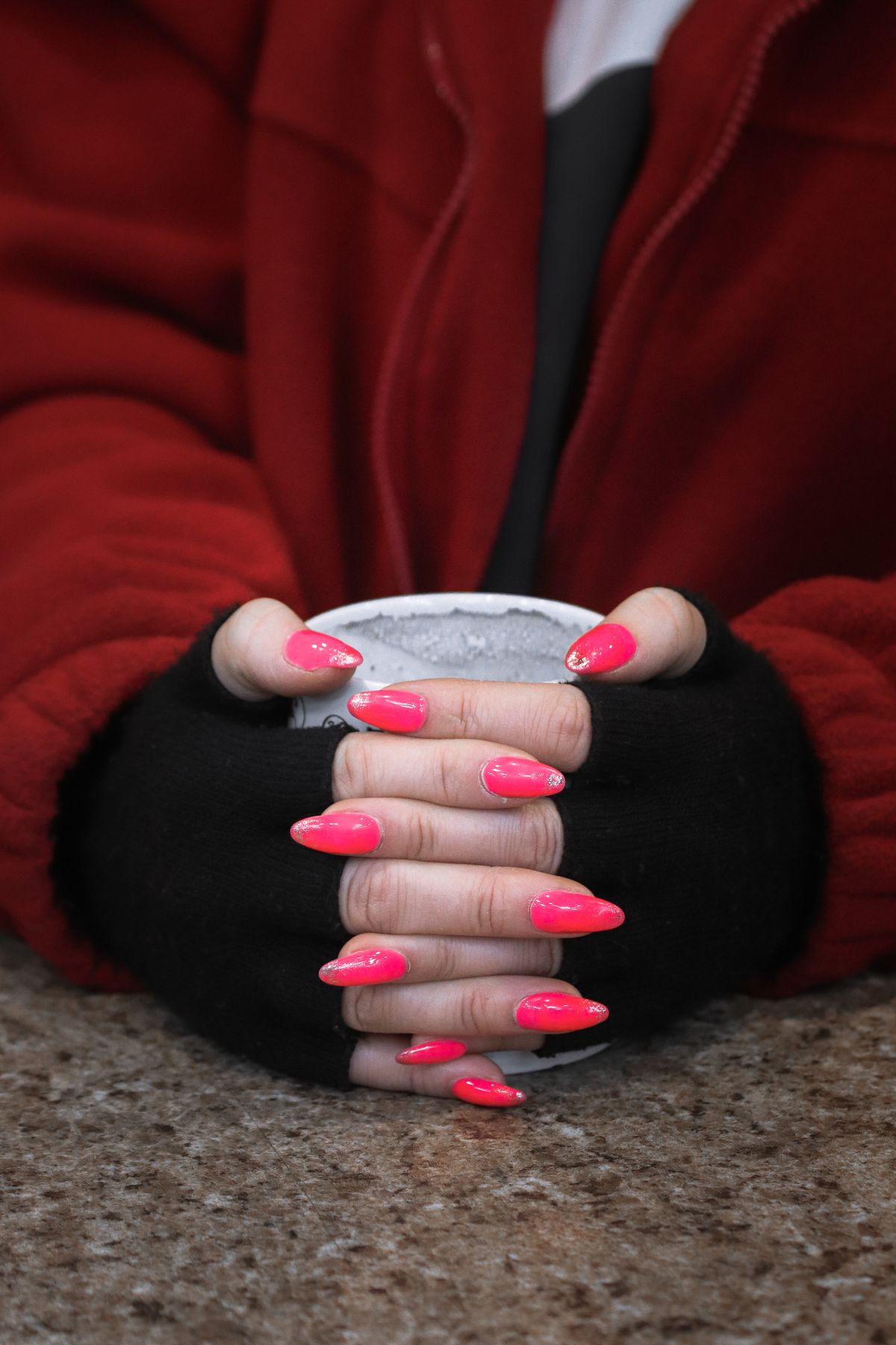 Close-up of a woman's hand with pink nails holding a mug. Warm vibes.