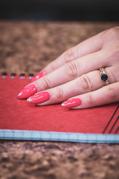 Free Close-up of a Person with Manicured Nails on a Notebook Stock Photo