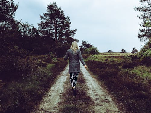 Woman in Grey Cardigan With Grey and Black Striped Pants Walking at the Pathway