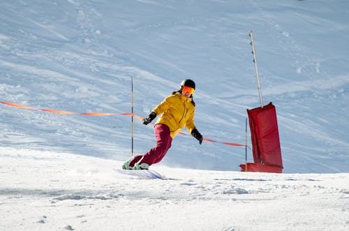 Free Person in a Yellow Jacket and Red Pants Snowboarding Stock Photo