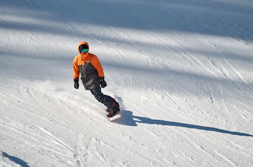 A Person Man in Winter Jacket Snowboarding on Snow Covered Mountain