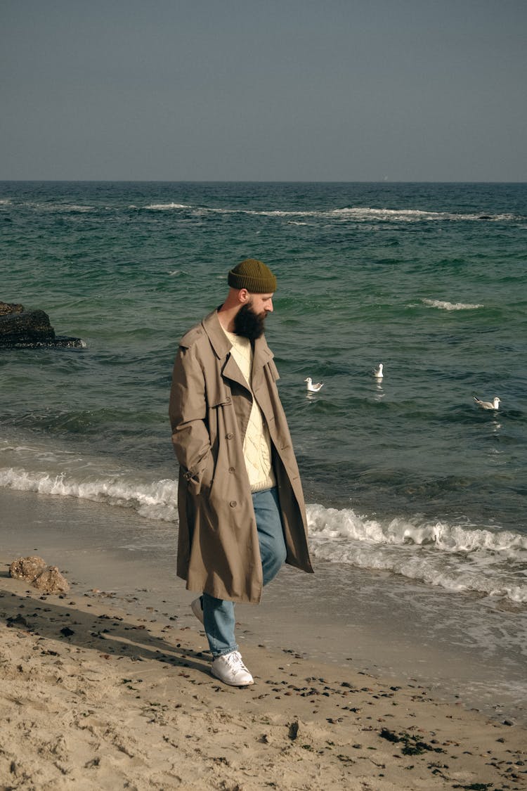 Man With Big Black Beard In Long Coat At Seashore On Sunny Day