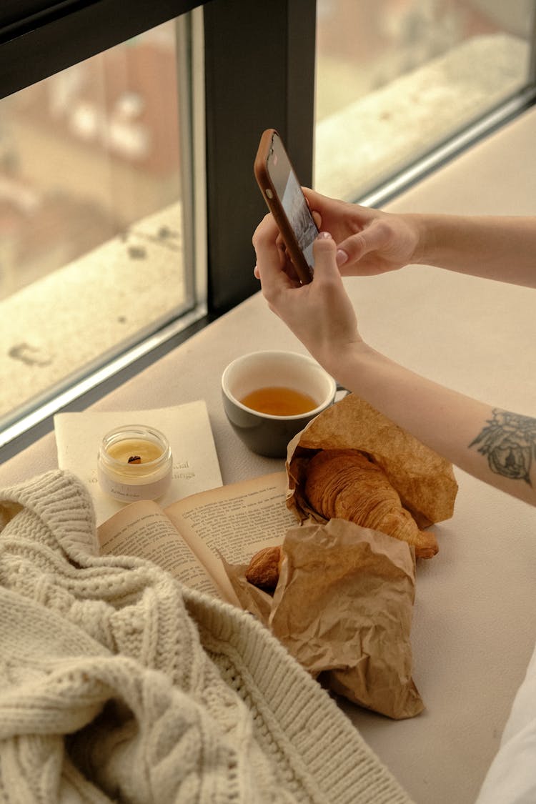 Unrecognizable Hands Checking Messages On Mobile Phone At Window Sill At Home