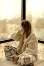Cross Legged Sitting Woman Holding Cup of Tea Looking Through Window