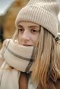 Young Blond Woman in Beige Knitted Hat and Warm Shawl Wrapped around Her Mouth