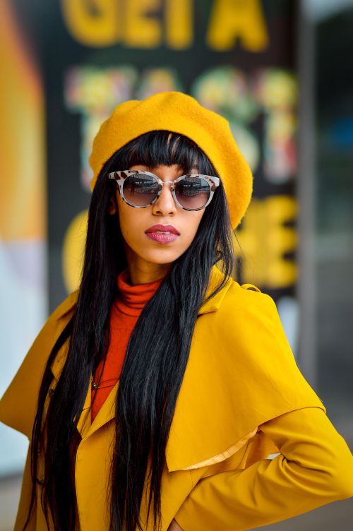 Free Fashionable woman with sunglasses in yellow outfit poses outdoors in Nairobi. Stock Photo