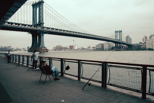 Individuals enjoying a leisurely day by the Manhattan Bridge, New York City waterfront.