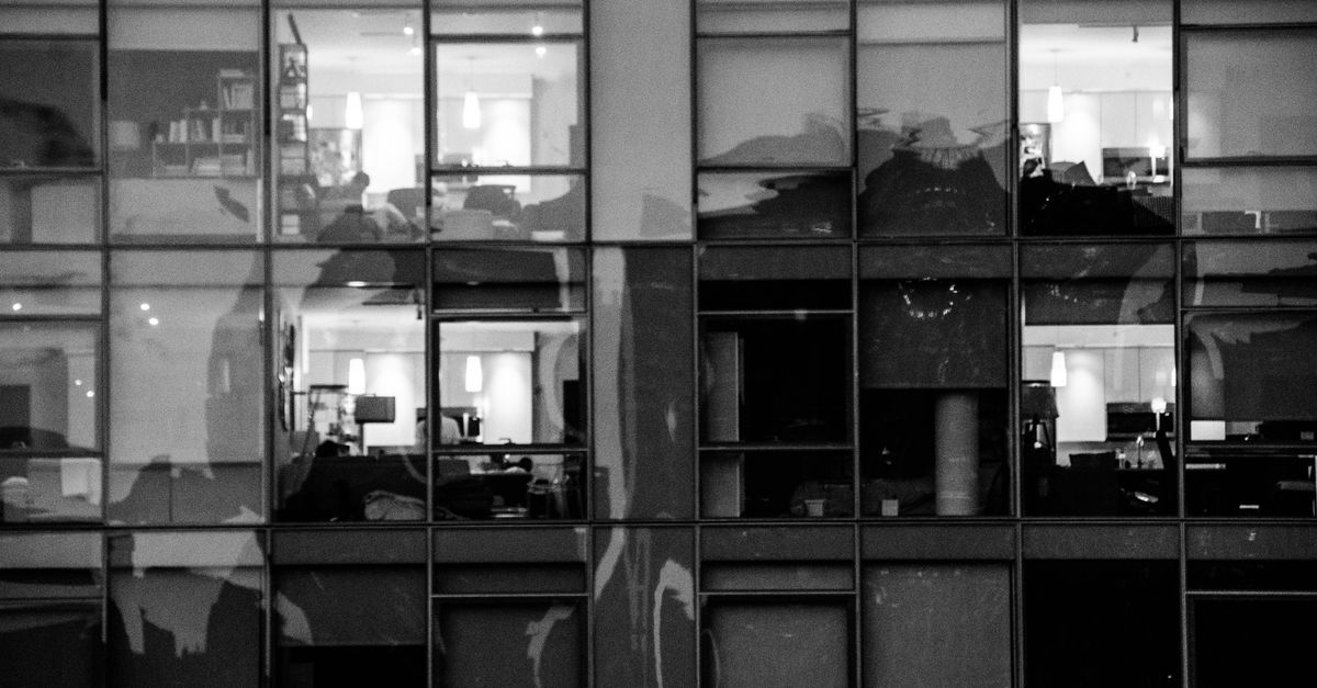 Reflejo urbano en blanco y negro capturado en la fachada moderna de un edificio de vidrio.