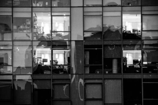Black and white urban reflection captured on a modern glass building facade.