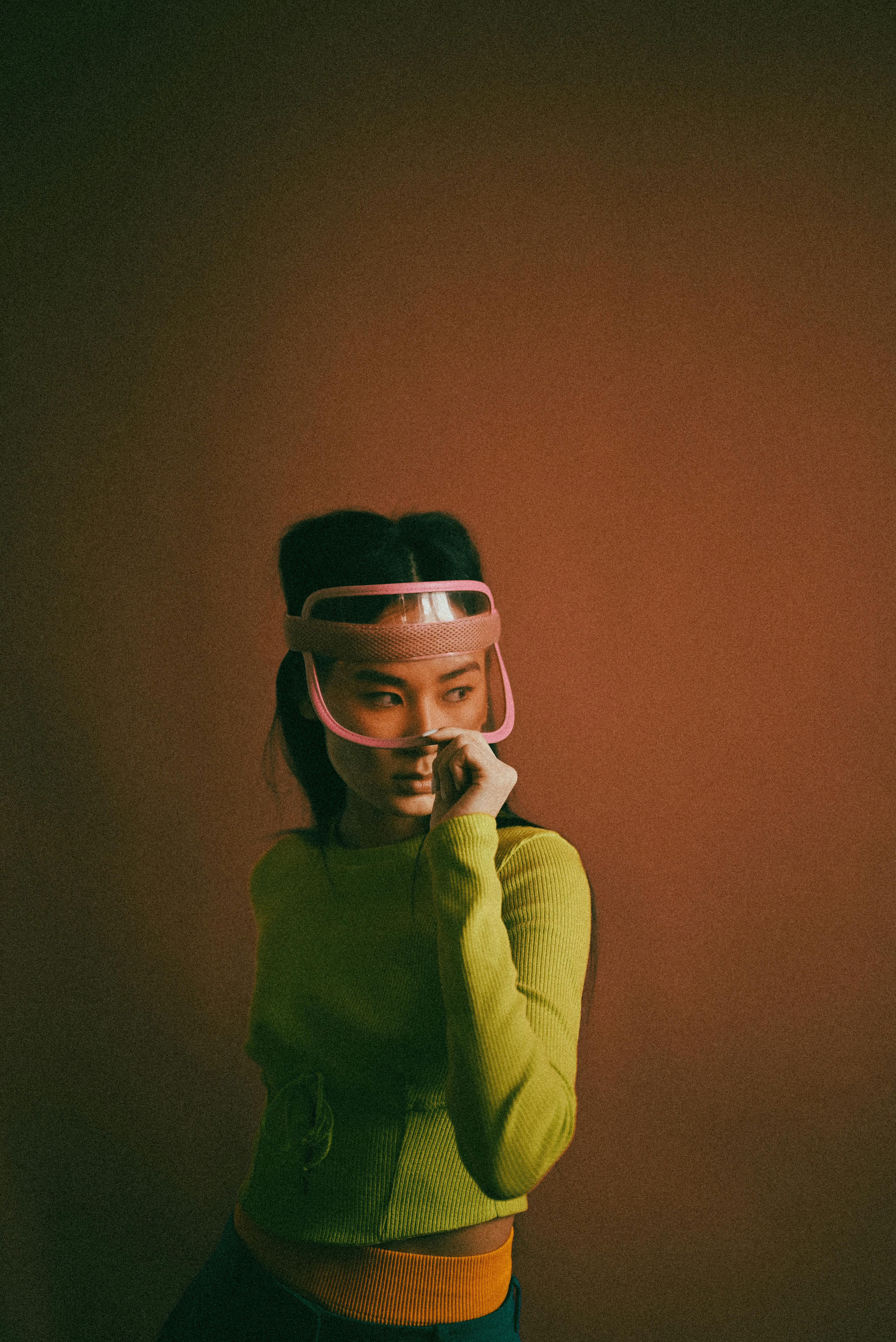 Portrait of a woman wearing a visor with a modern vibe, set against an orange studio backdrop.