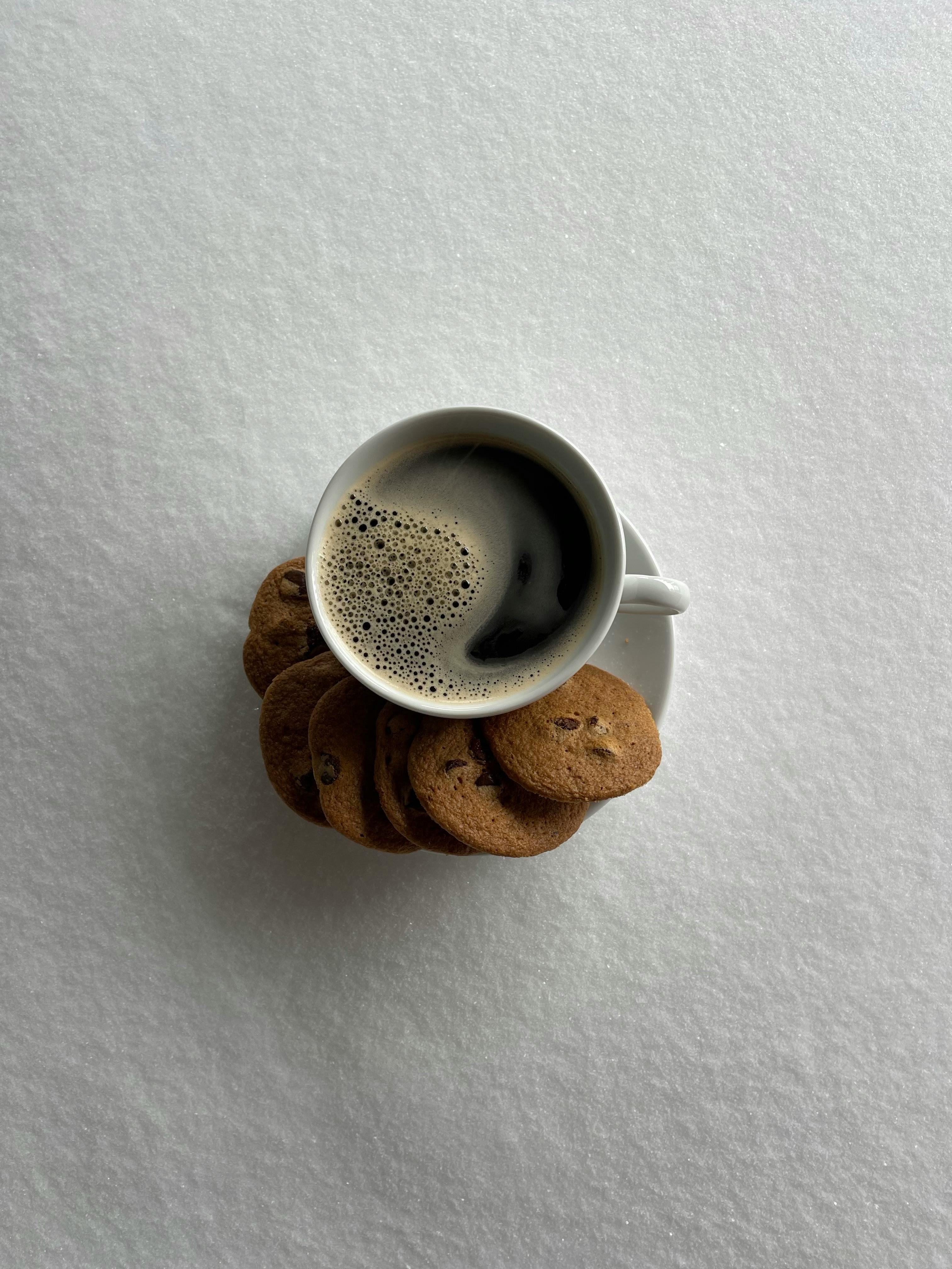 white ceramic mug with coffee on brown wooden coaster