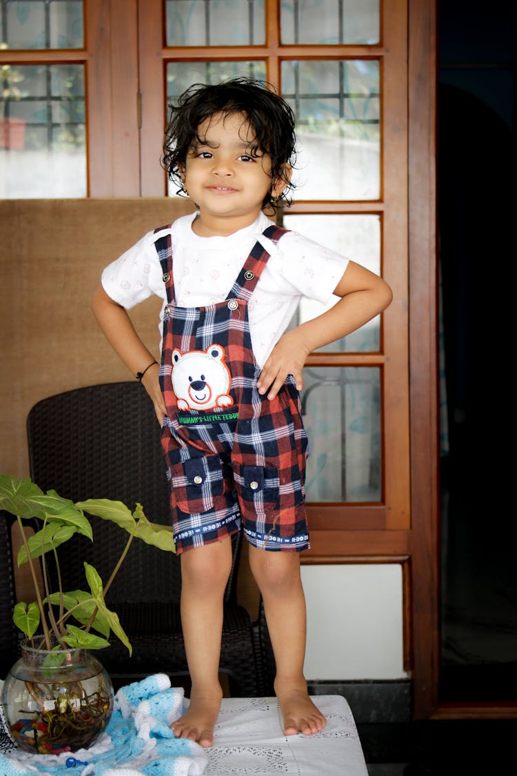 Brunette Girl Wearing Checked Dungarees Standing On A Table