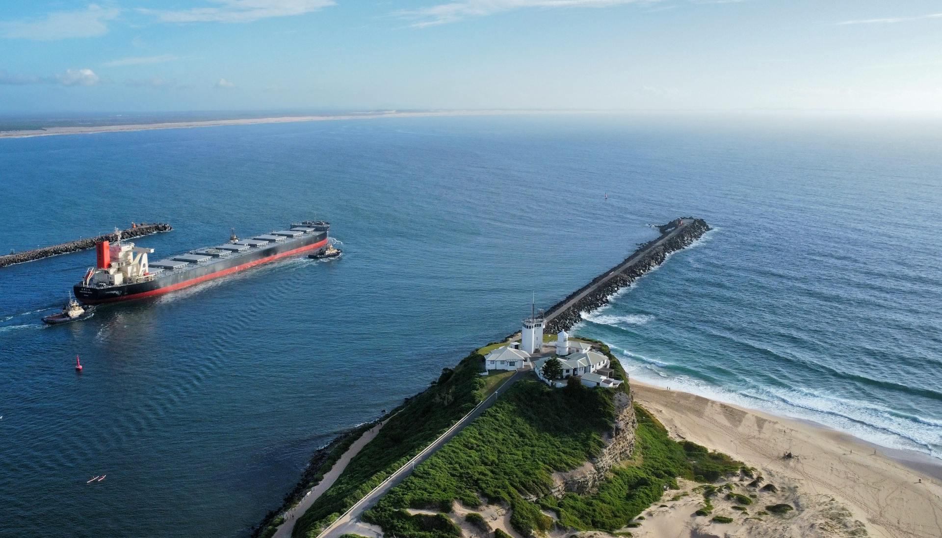 Aerial view of Nobbys Lighthouse overlooking a coal ship entering Newcastle Harbour on a clear day.