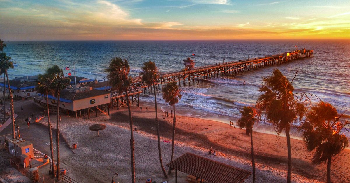 A breathtaking sunset view from above of a scenic beach with a long pier extending into the ocean.