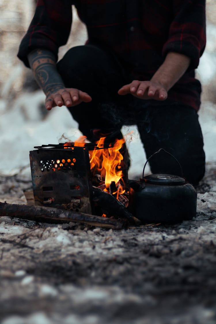 Man Warming Hands Over Campfire