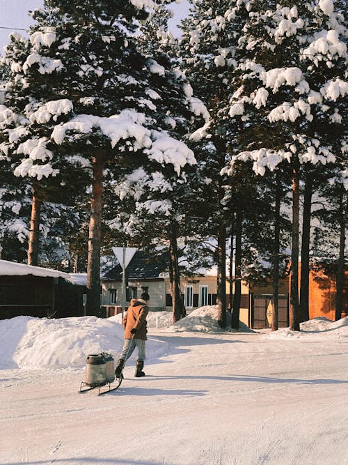 A Person in Brown Jacket Walking on a Snow Covered Ground