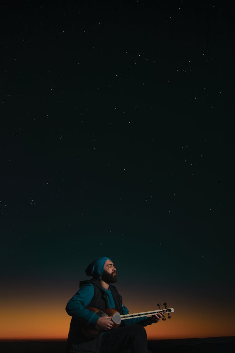 A Man Playing A Tar Under The Starry Sky