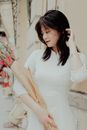 Woman in Form-fitting White Dress Holding Bouquet of Flowers