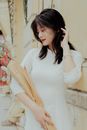 Woman in Form-fitting White Dress Holding Bouquet of Flowers