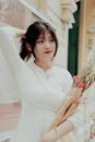 Woman in Form-fitting White Dress Holding Bouquet of Flowers