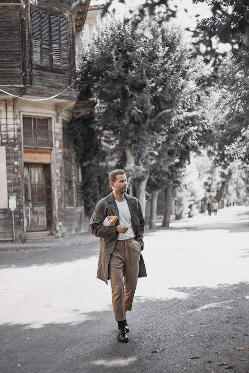 A Man in Gray Coat Walking on the Street