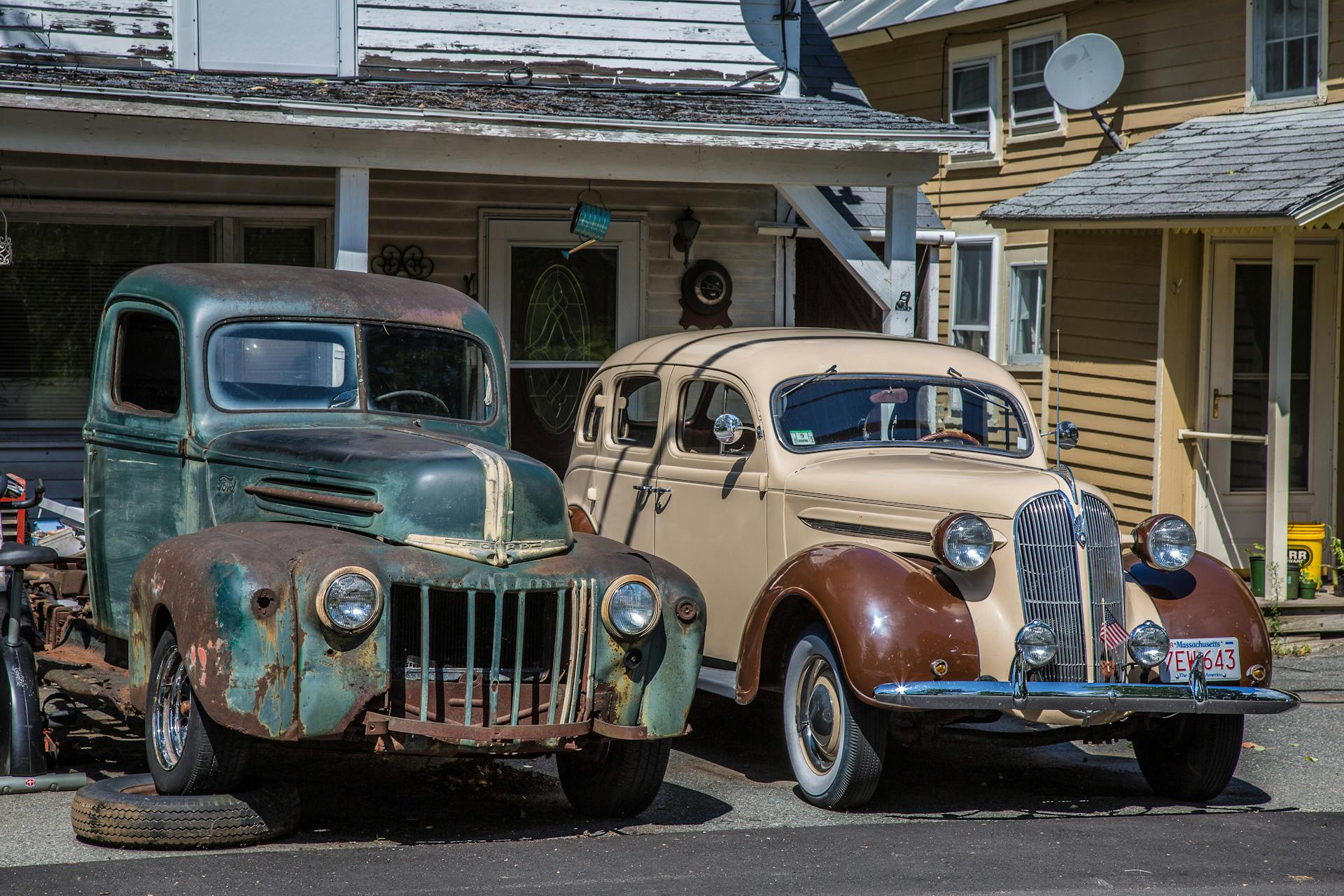 Two vintage cars parked outdoors in Shelburne Falls, MA, showcasing classic automotive design.