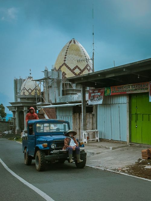 Free A blue vintage vehicle parked on a city street beside a mosque under construction. Stock Photo