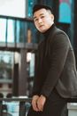 Man in Blazer and Turtleneck Sitting on Railing