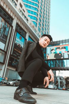 Stylish man posing by skyscrapers in a modern city downtown.