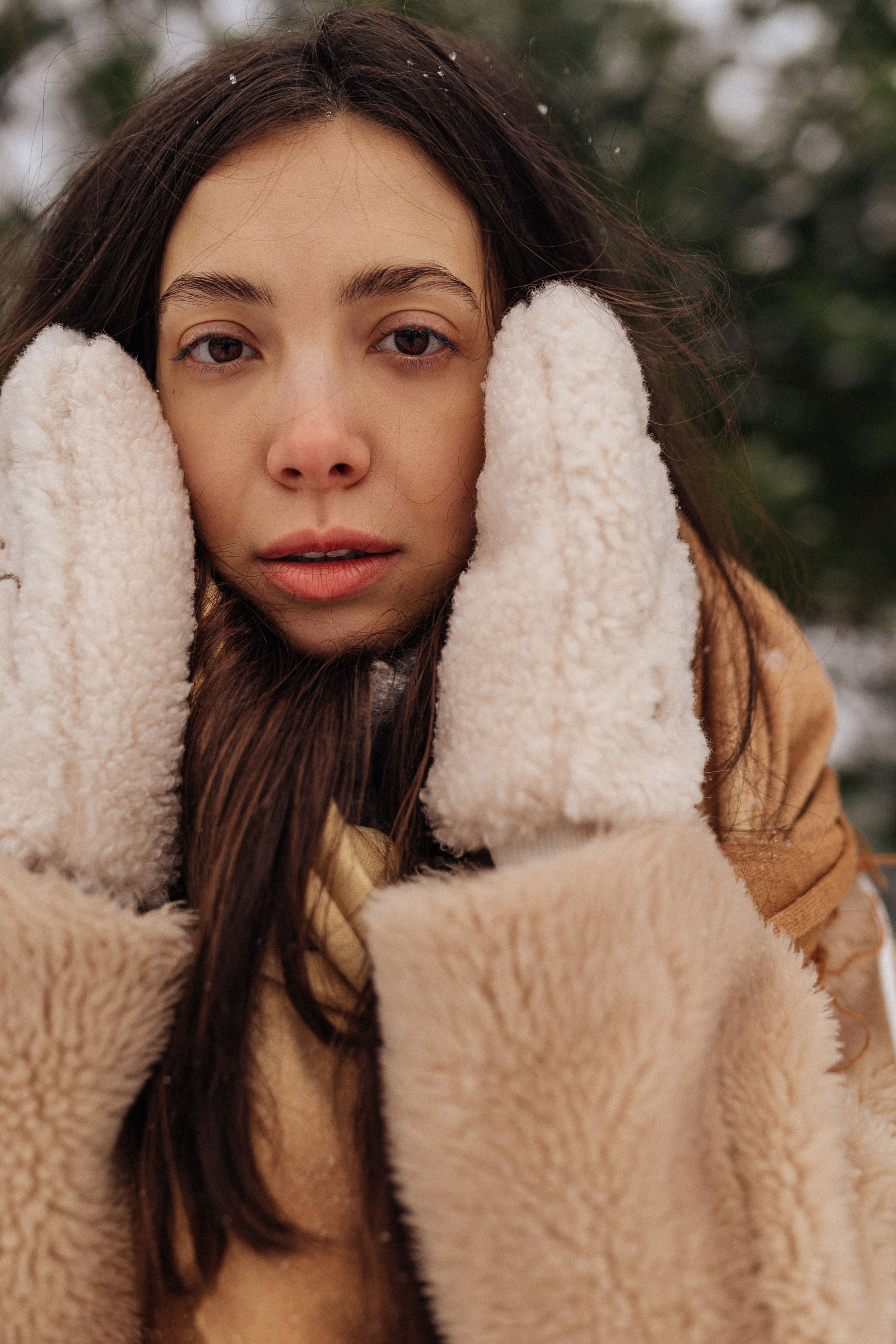 Young woman in winter fur coat and mittens embracing warmth amidst a snowy Moscow background.