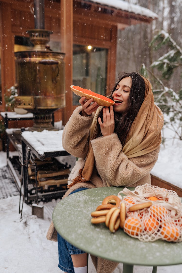 Woman Sitting At An Outdoor Table In Winter And Eating 