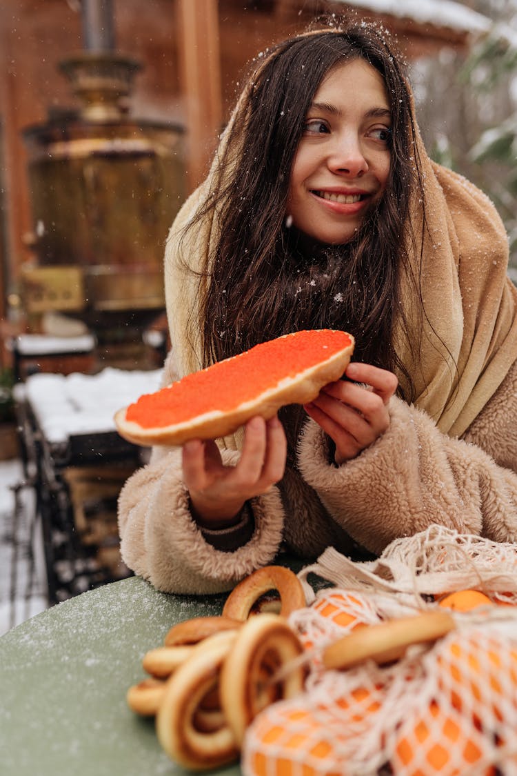 Young Woman Eating Bread On A Cold Winter Day 