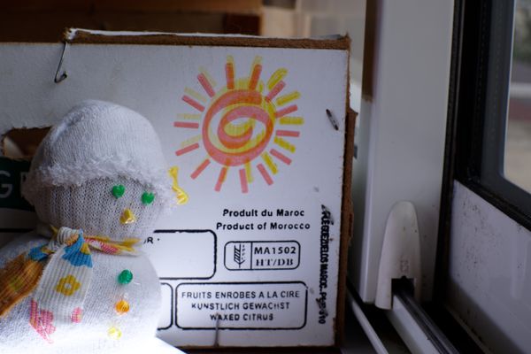 Handmade sock snowman before a Moroccan citrus crate with sun logo