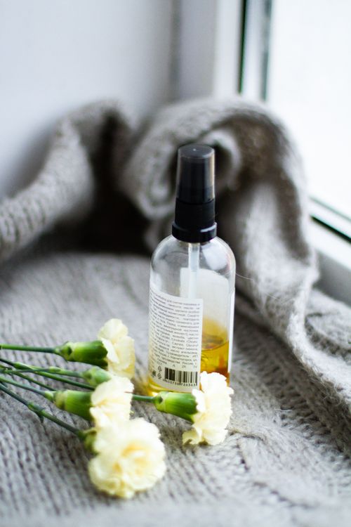 Free Glass spray bottle with flowers on knitted cloth, ideal for beauty and relaxation themes. Stock Photo