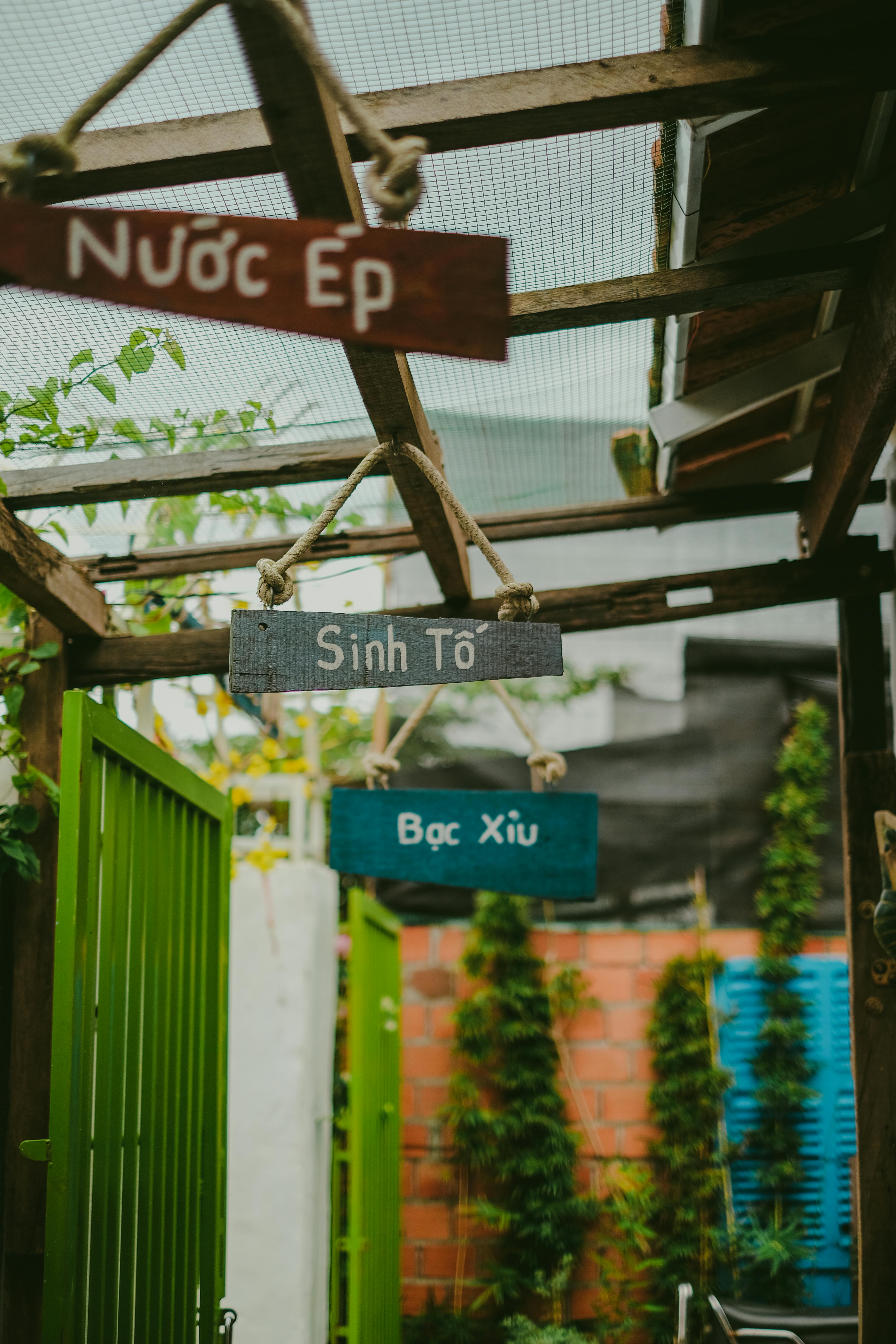 Decorative signs with non-Latin script hanging in an outdoor garden area.