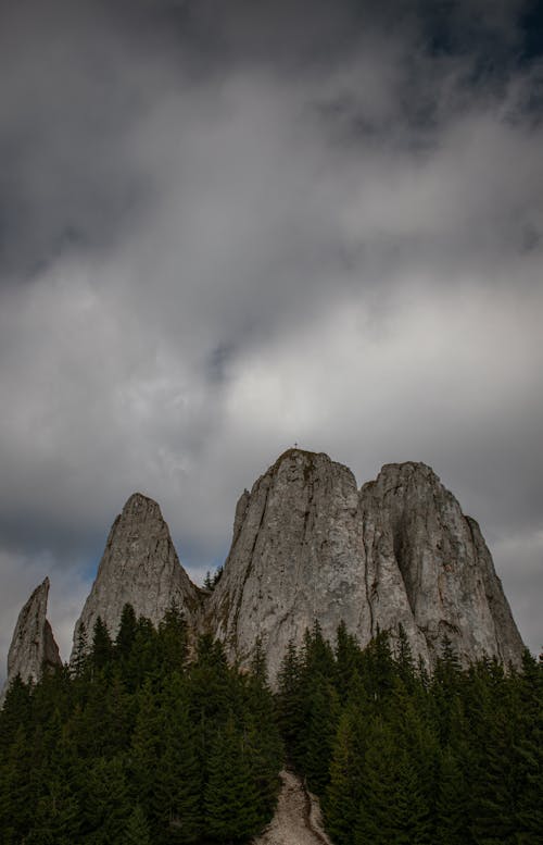 A Low Angle Shot of a Rocky Mountain Under the Cloudy Sky